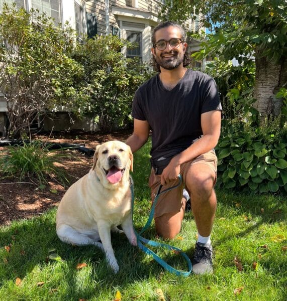 Ajay posing with a smiling yellow lab.